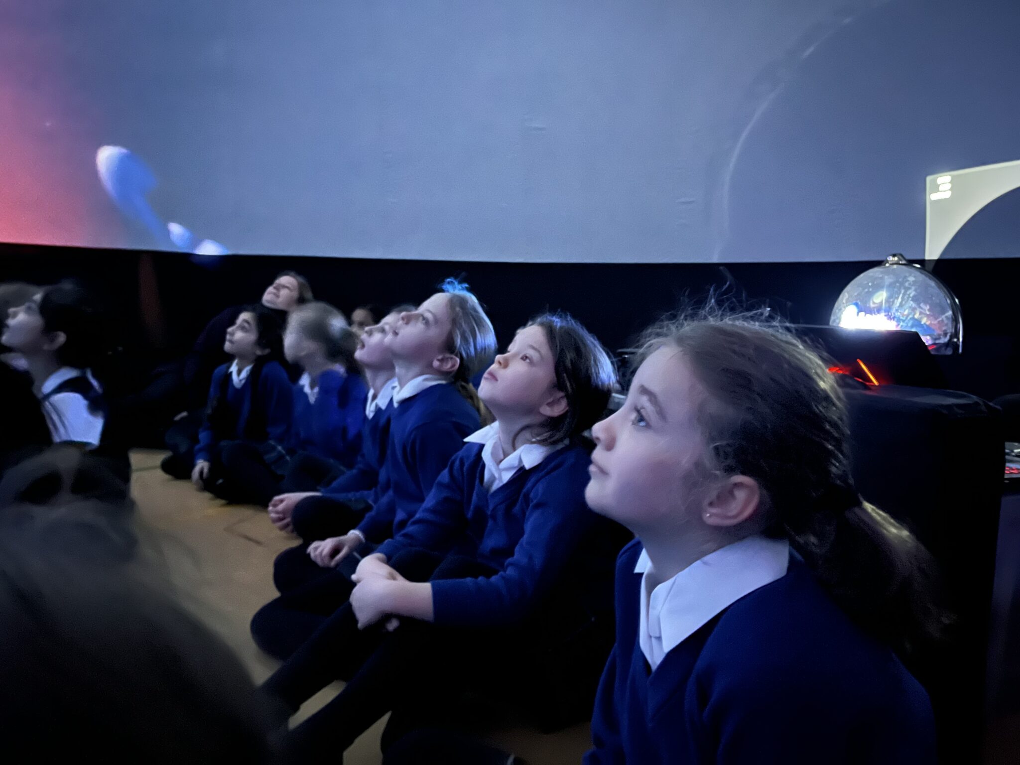 students looking up at a planetarium